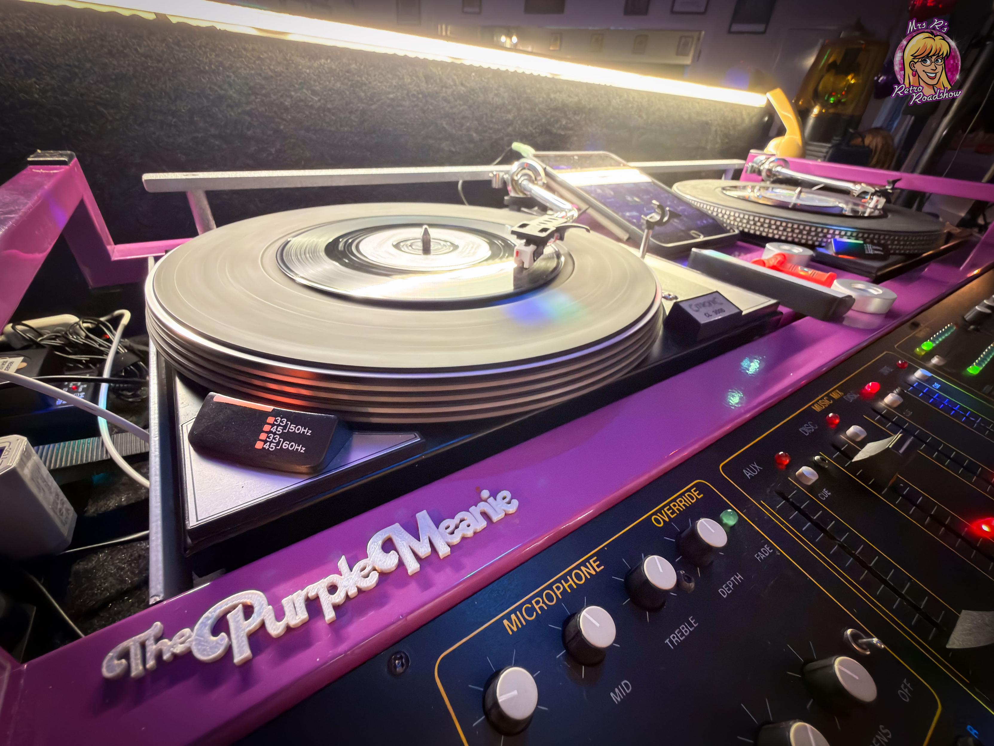 A 1980s disco console coloured purple, with the legend "The Purple Meanie". The left turntable is playing a record. Some of the controls are visible to the bottom right.
